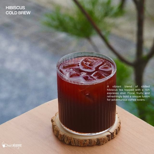 Hibiscus cold brew in a ribbed glass on a wood coaster