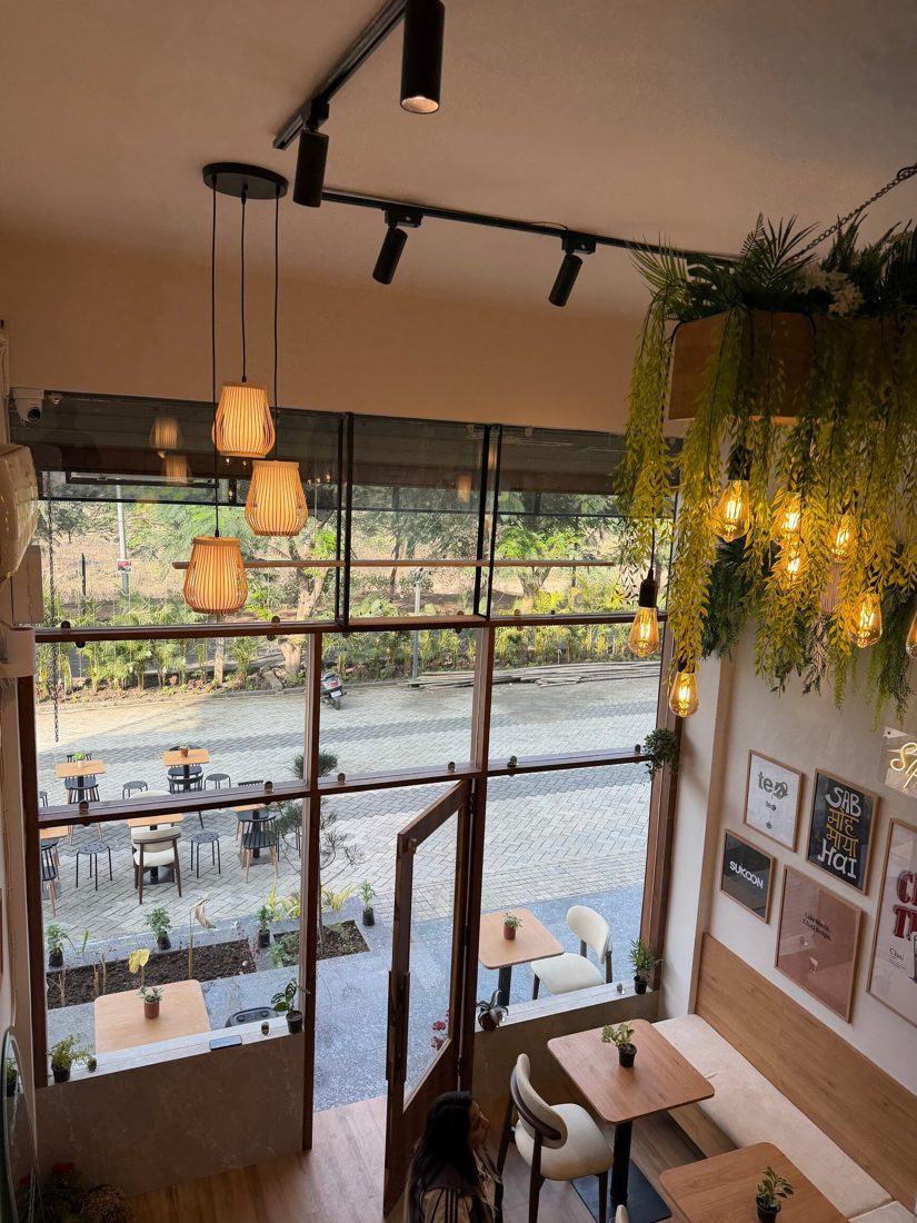 Chai Mantralaya Kolar Road: pendant lamps, hanging plants and a tall window over Augustus Business Street
