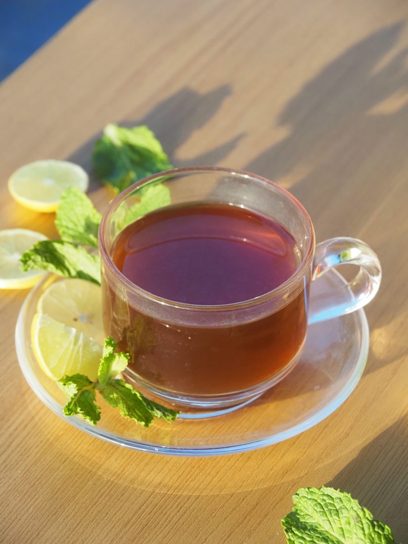 Lemon mint tea in a glass cup with lemon slices